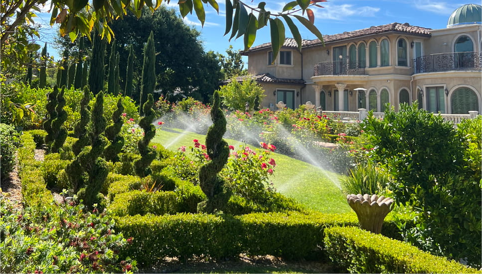 a lawn with a house and a sprinkler system